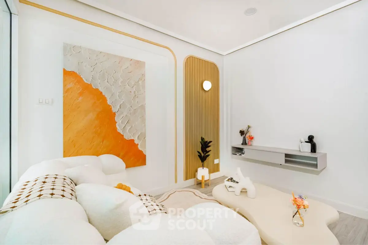 Modern living room with stylish decor and cozy white sofa, featuring abstract wall art and elegant lighting.