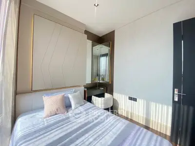 Modern bedroom with stylish decor and ample natural light, featuring a cozy bed and elegant mirror.