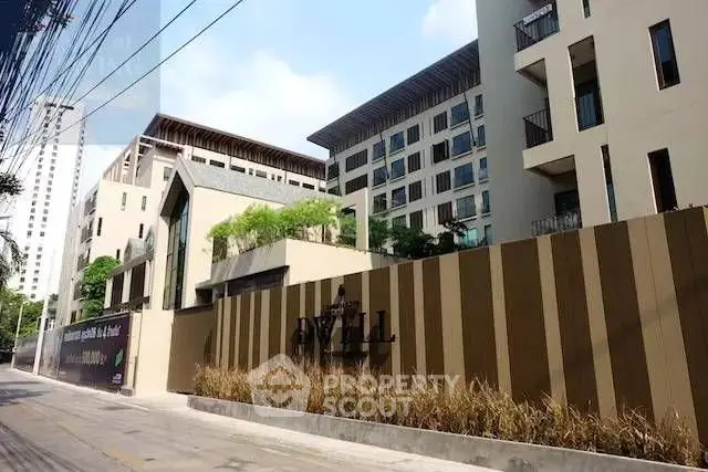Modern apartment building exterior with lush greenery and stylish design in urban setting.