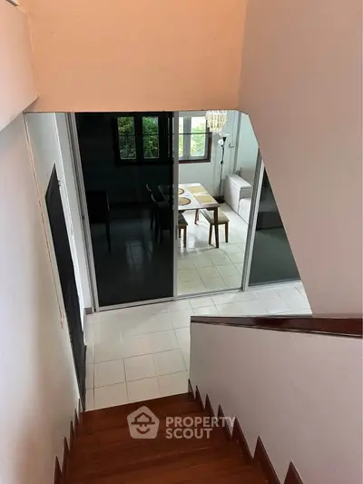 Modern interior with staircase leading to a stylish living room with glass doors and elegant furniture.