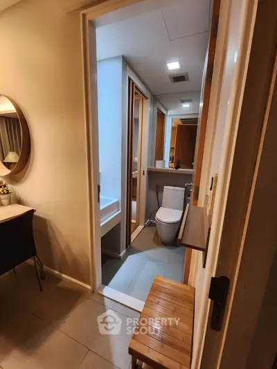 Inviting modern bathroom with sleek finishes, featuring a well-lit vanity area, large mirror, and a comfortable wooden bench, perfect for a relaxing retreat in a cozy home.