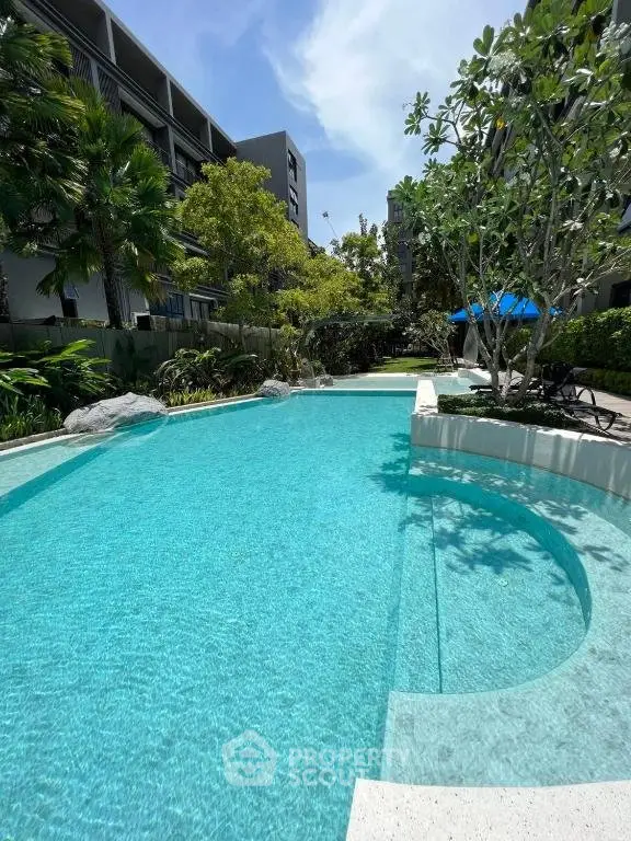 Luxurious residential pool area with lush greenery and modern architecture.