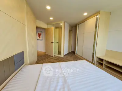 Modern bedroom with stylish decor and ample natural light, featuring built-in wardrobes and elegant flooring.