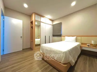 Modern bedroom with sleek design, featuring a comfortable bed, built-in wardrobe, and stylish wooden flooring.
