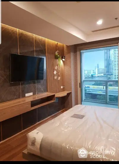 Modern bedroom with city view, featuring a wall-mounted TV, stylish wood paneling, and a large window.