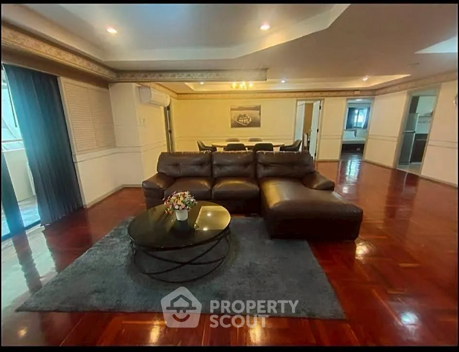 Spacious living room with elegant leather sofa and polished wooden floors in a luxurious apartment.