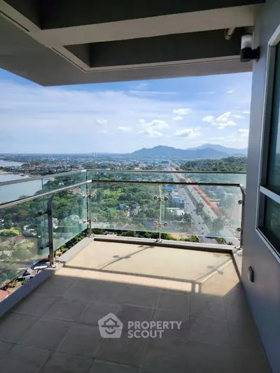 Stunning balcony view with glass railing overlooking scenic landscape and mountains.