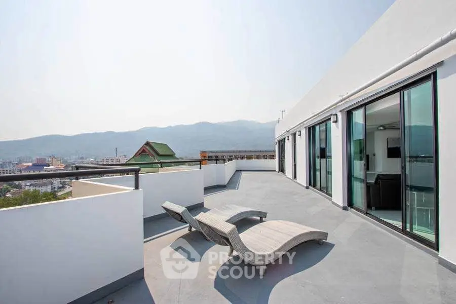 Spacious rooftop terrace with mountain views and modern lounge chairs.