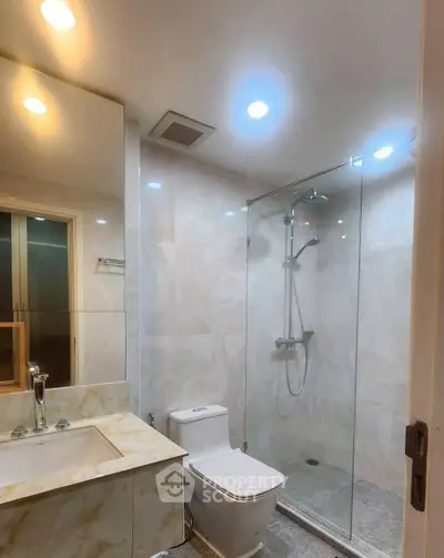 Modern bathroom with glass shower and elegant marble sink in luxury apartment.