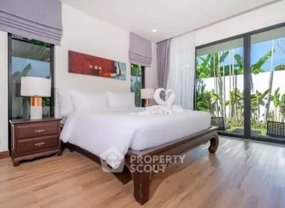 Luxurious bedroom with elegant decor and garden view through large windows.