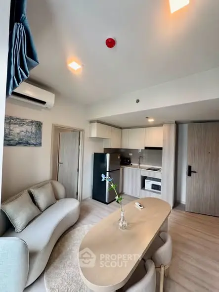 Modern living room with open kitchen, featuring sleek furniture and contemporary design.