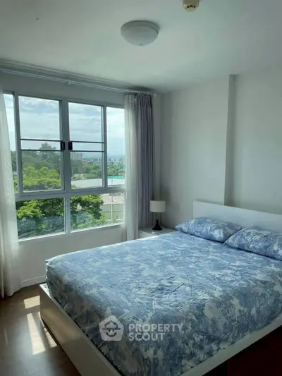 Bright bedroom with large window and scenic view, featuring a cozy bed and modern decor.