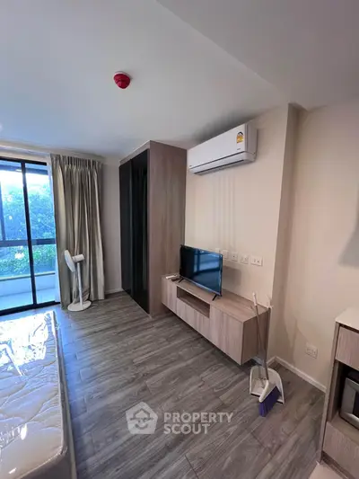 Modern bedroom with balcony access, featuring sleek flooring and air conditioning for comfort.