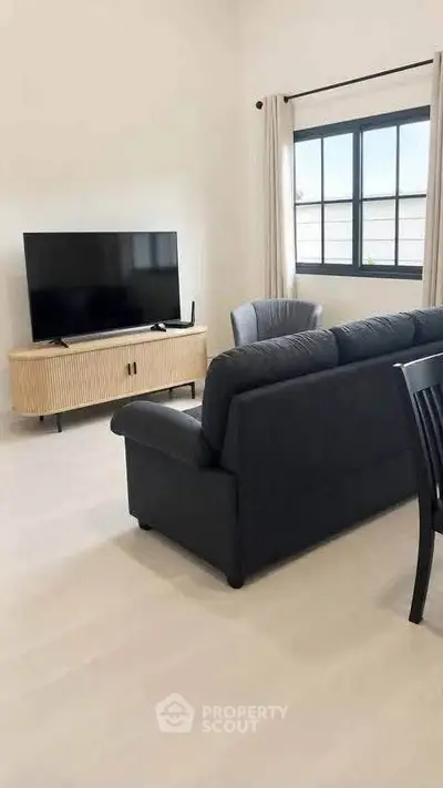 Modern living room with sleek black sofa and large TV, perfect for relaxation and entertainment.