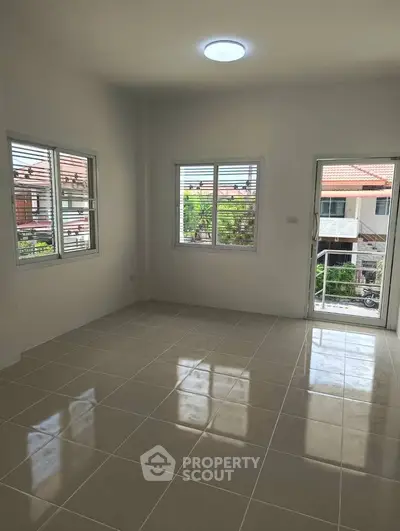 Spacious and bright room with tiled flooring and large windows offering a pleasant view.