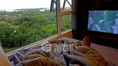 Cozy bedroom with stunning green view through large windows, perfect for relaxation and tranquility.