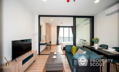 Modern studio apartment with seamless living and sleeping areas, featuring a plush sofa, flat-screen TV, and a cozy bedroom with balcony access for an airy, open feel.