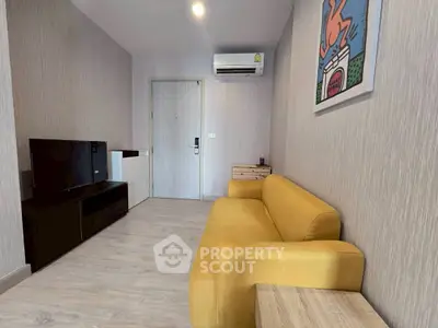 Modern living room with yellow sofa and wall art, featuring sleek TV unit and air conditioning.