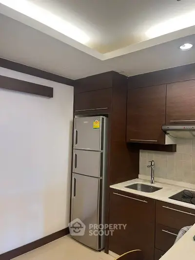 Modern kitchen with sleek cabinetry and stainless steel fridge in a stylish apartment.