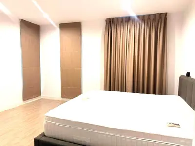 Spacious bedroom with elegant curtains and a comfortable bed in a modern apartment.