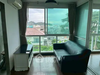 Charming living room with large windows offering a scenic view, featuring a cozy sofa and modern decor.
