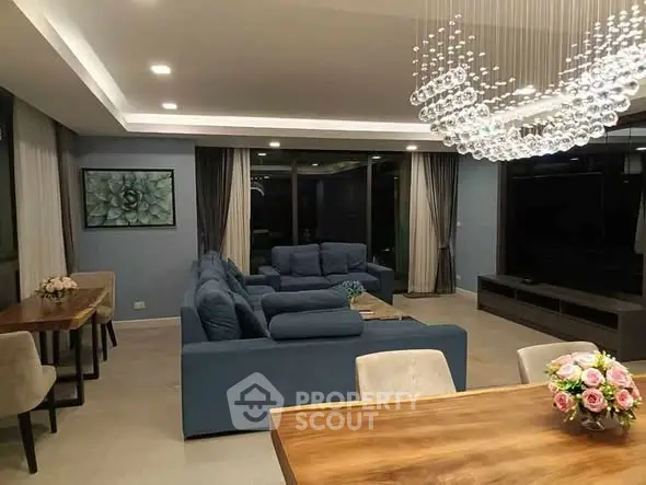 Luxurious living room with modern chandelier and plush blue sofas