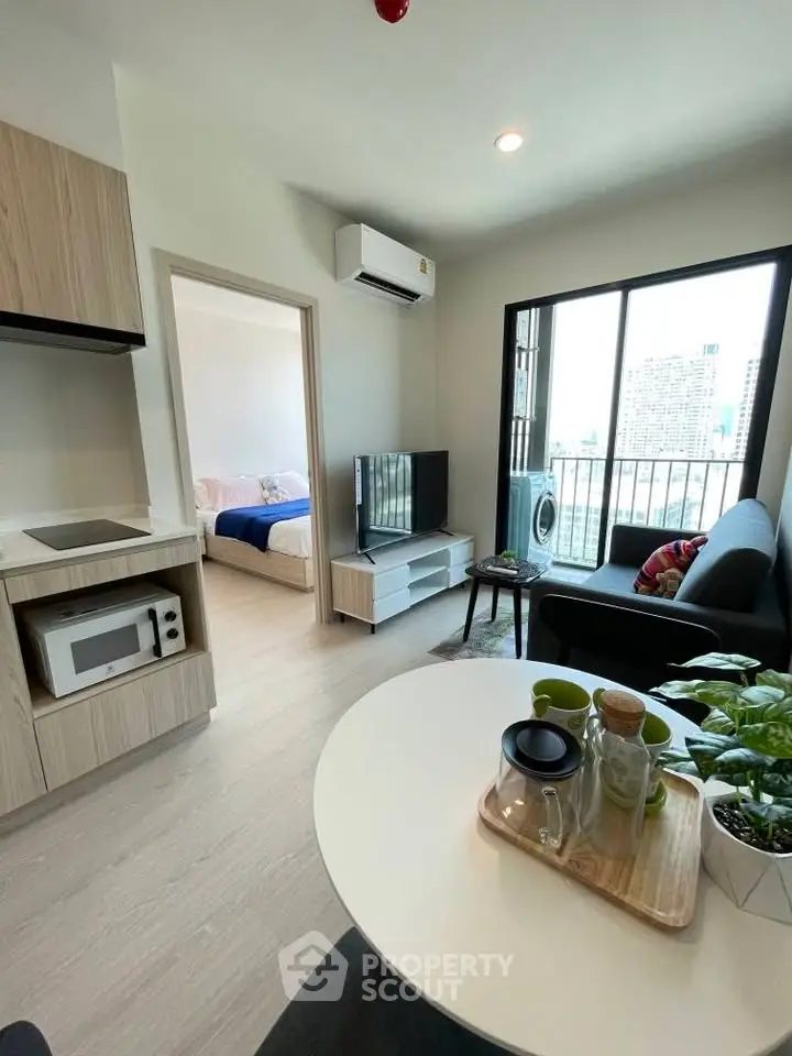 Modern living room with open kitchen and city view, featuring cozy furniture and natural light.