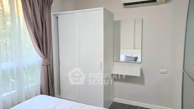 Cozy bedroom with white wardrobe and air conditioning, perfect for a comfortable living experience.