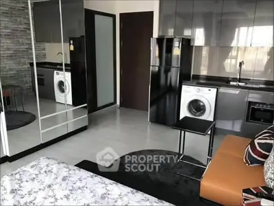 Modern studio apartment with sleek kitchen, washing machine, and mirrored wardrobe.