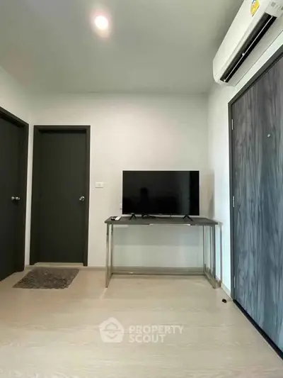 Modern living room with sleek TV setup and air conditioning in a stylish apartment.
