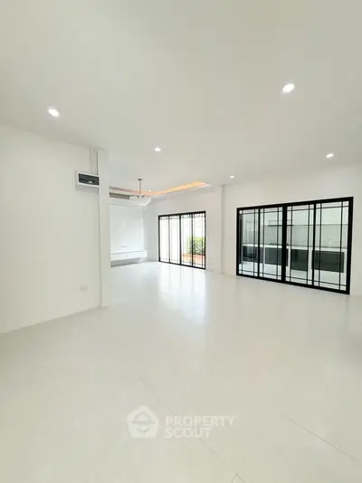 Spacious modern living room with large windows and elegant lighting