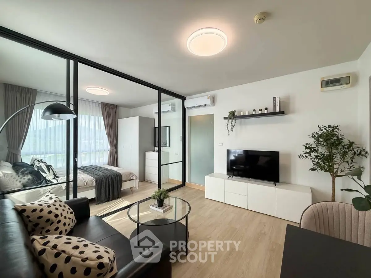 Modern living room with glass partition, sleek furniture, and natural light in a stylish apartment.