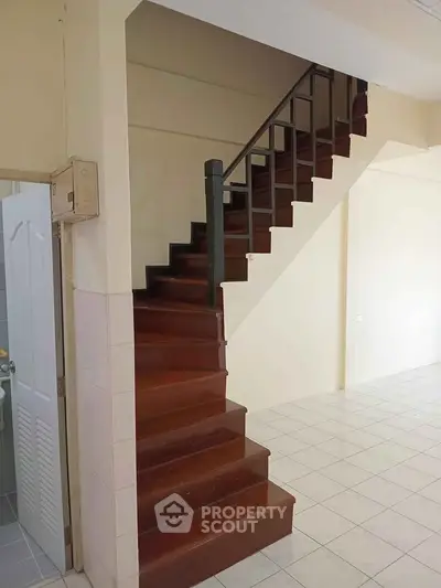 Spacious interior with wooden staircase and tiled flooring, ideal for modern living.