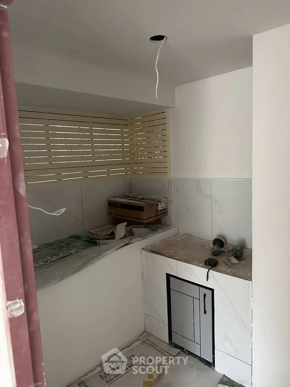 Compact kitchen under renovation with marble countertops and modern cabinetry.