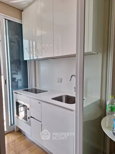 Modern compact kitchen with sleek white cabinets and built-in appliances
