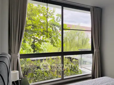 Bright bedroom with large window offering lush garden view, enhancing natural light and tranquility.