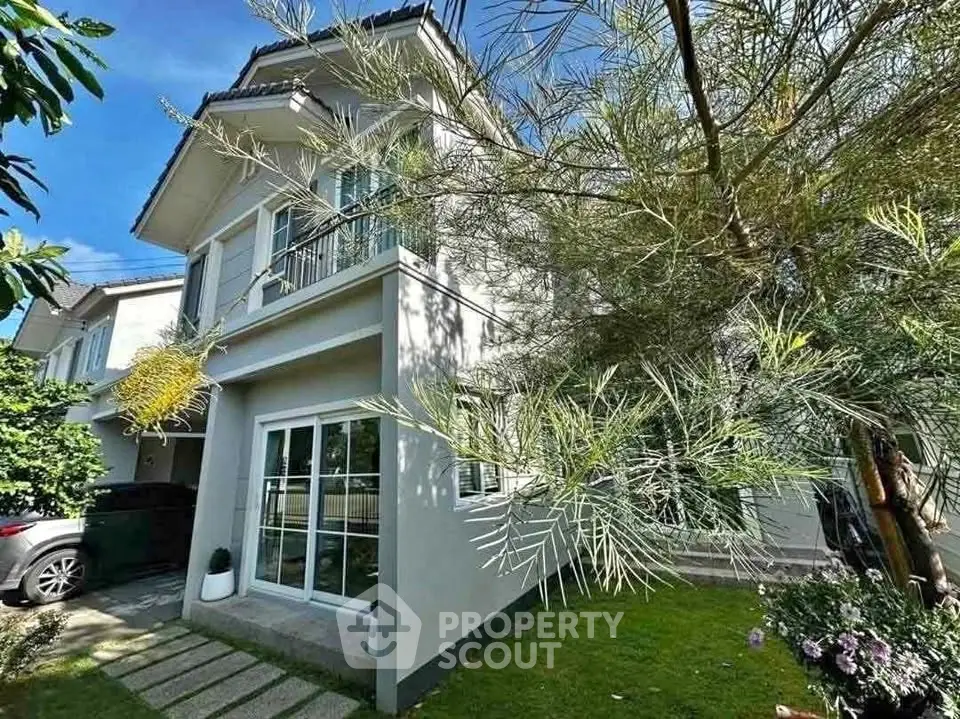 Charming two-story house with lush garden and driveway in a serene neighborhood.