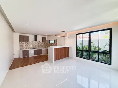 Spacious modern kitchen with open layout and large window overlooking garden