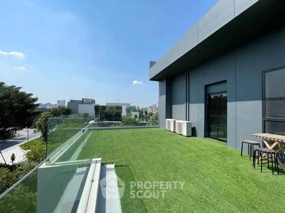 Modern rooftop terrace with artificial grass and city view, perfect for relaxation and entertainment.