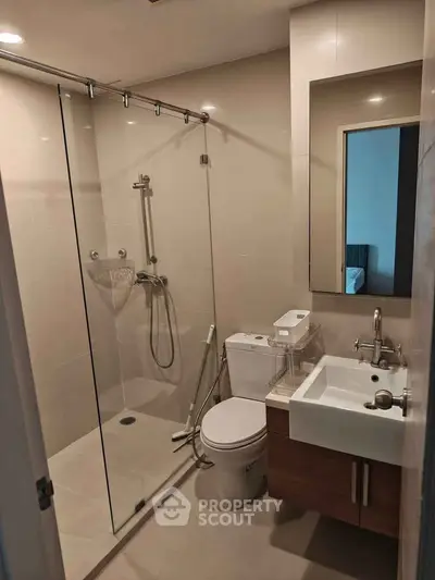 Modern bathroom with glass shower enclosure and sleek fixtures in a contemporary apartment.