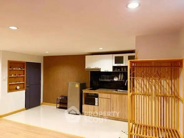 Modern kitchen with sleek appliances and stylish wooden accents in a cozy apartment setting.