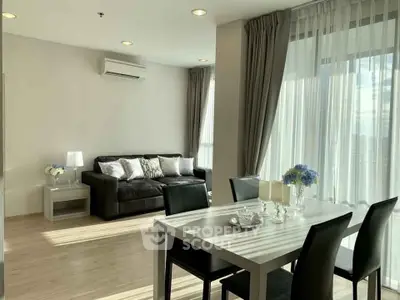Modern living room with dining area, featuring large windows and elegant decor.