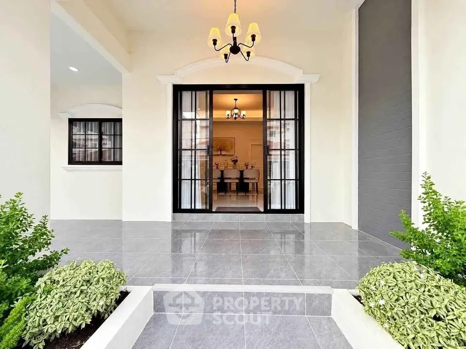 Elegant entrance with modern glass doors and lush greenery