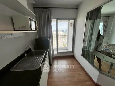 Compact kitchen with city view, featuring modern appliances and sleek design in high-rise apartment.