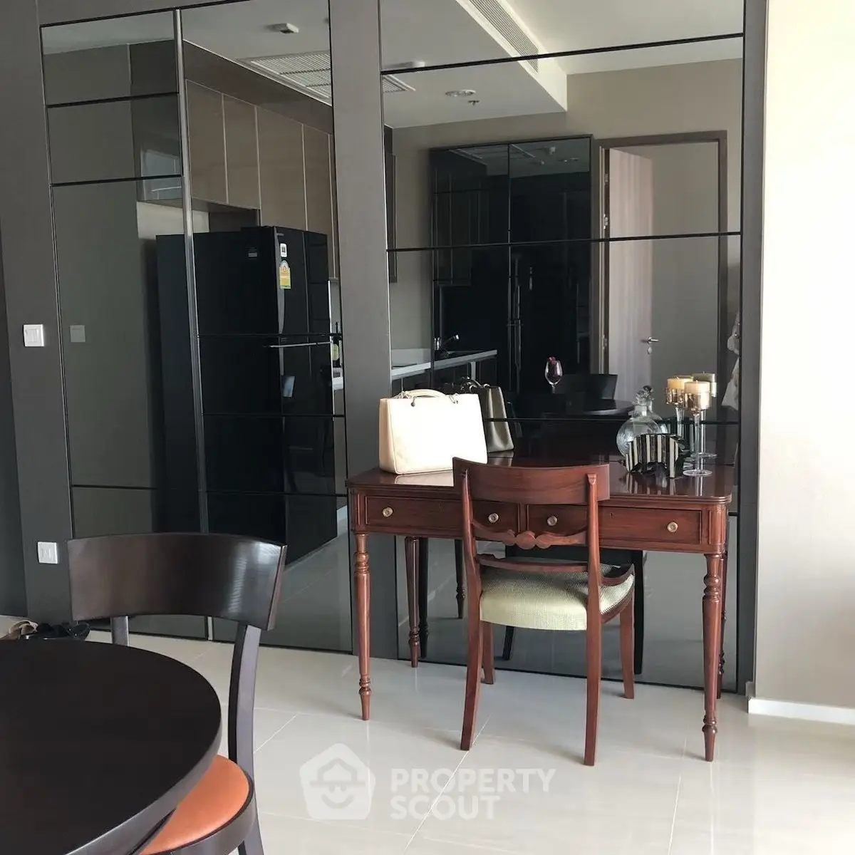 Elegant dining area with mirrored wall and vintage wooden table in modern apartment.