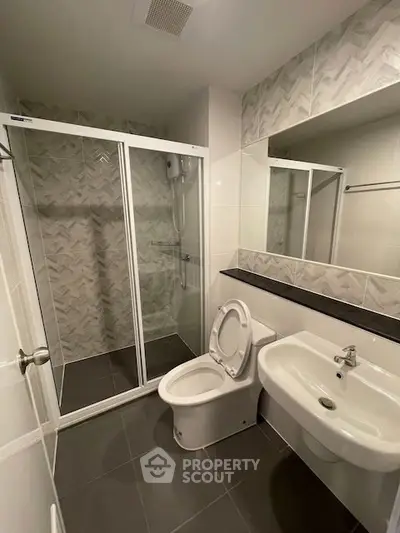 Modern bathroom with glass shower enclosure and sleek fixtures in contemporary apartment.