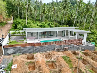 Modern luxury villa with pool surrounded by lush greenery and palm trees, offering serene tropical living.