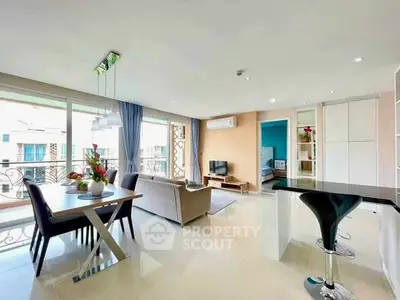 Spacious modern living room with open kitchen and dining area, featuring elegant decor and natural light.