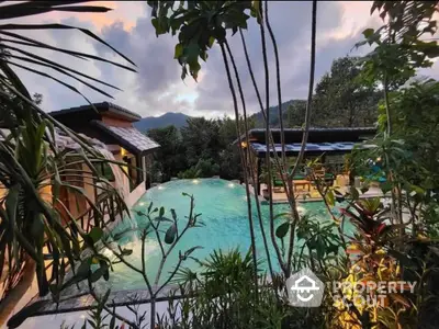 Stunning tropical poolside view with lush greenery and mountain backdrop, perfect for serene living.