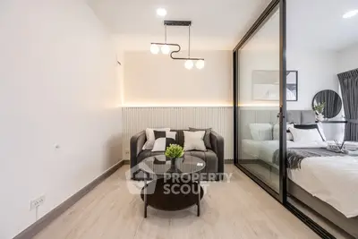 Modern living room with stylish decor and glass partition to bedroom